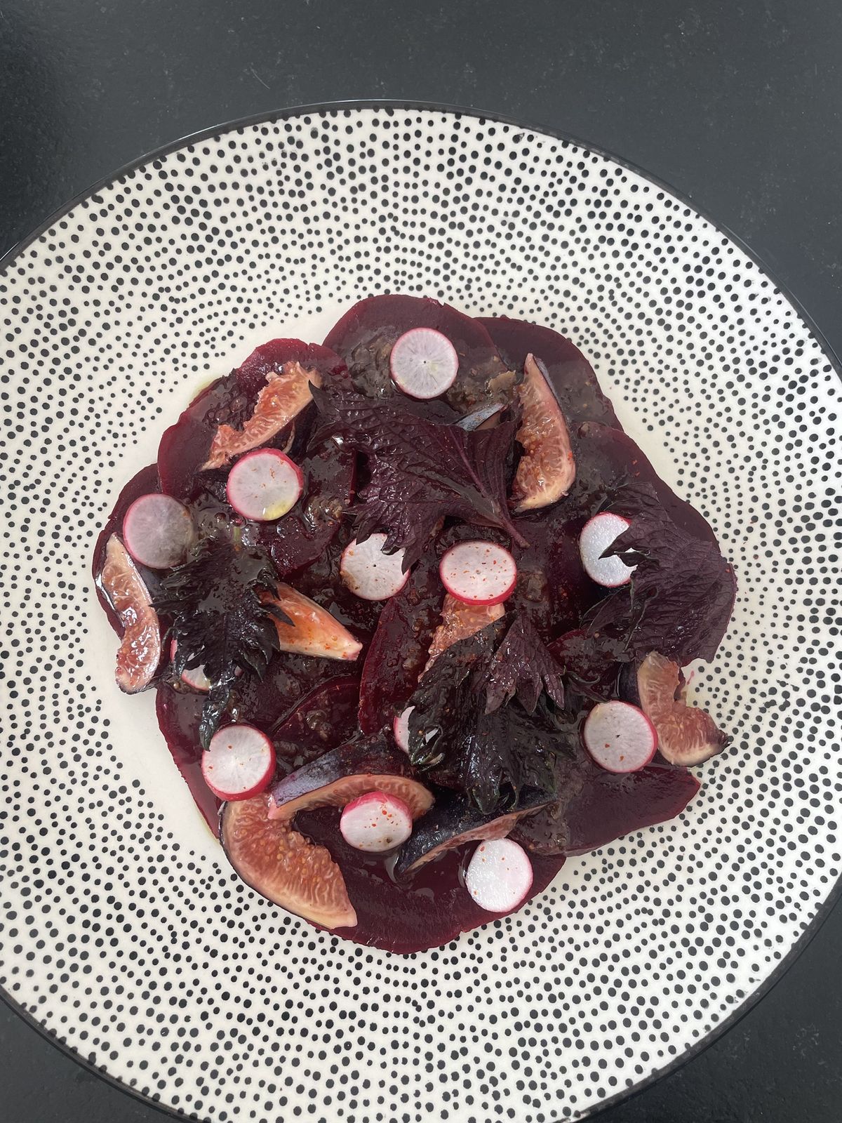 Carpaccio de betterave, figues et radis sur une assiette à pois